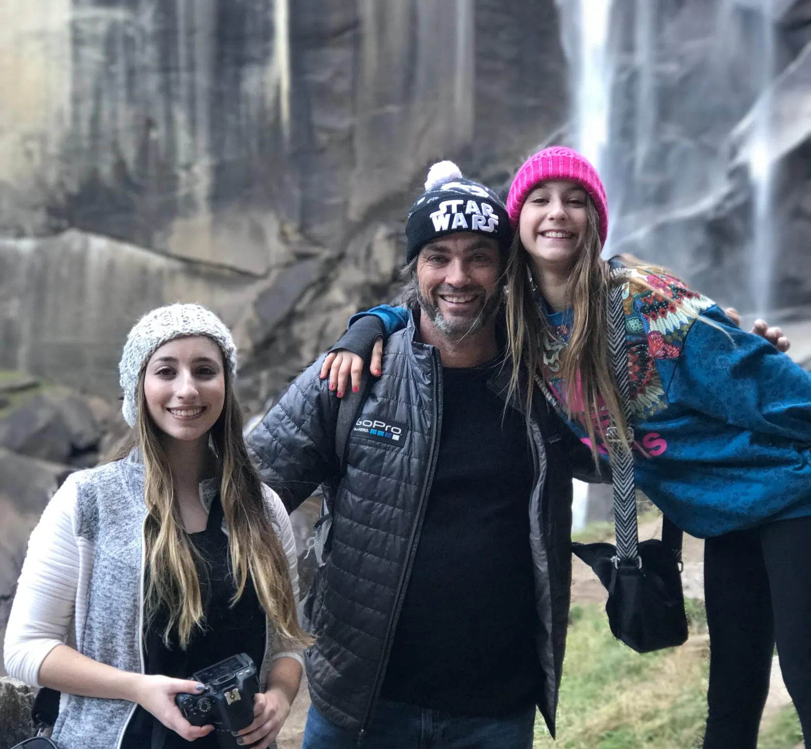 Greg and family smiling in front of a waterfall at Yosemite